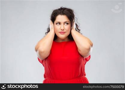 noise, stress and people concept - woman in red dress closing her ears by hands over grey background. woman in red dress closing her ears by hands
