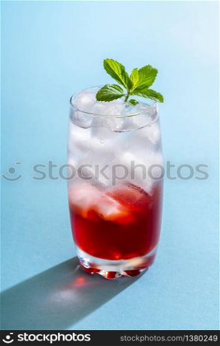 Non-alcoholic drink with water, ice cubes and strawberries syrup. Strawberries lemonade in a glass full of ice cubes. Mineral water glass filled with ice cubes and strawberries syrup
