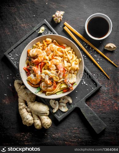 Noodles in a plate on a cutting Board with ginger and soy sauce. On dark rustic background. Noodles in a plate on a cutting Board with ginger and soy sauce.