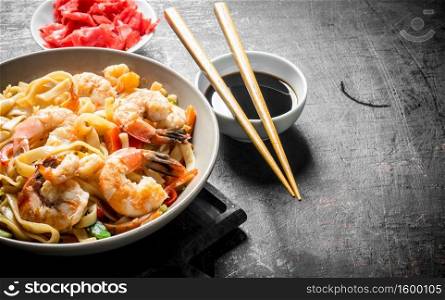 Noodles in a plate with shrimp and vegetables on the cutting Board. On dark rustic background. Noodles in a plate with shrimp and vegetables on the cutting Board.
