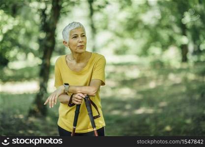 Nordic walking - active senior woman taking a break, enjoying the nature. Nordic Walking - Active Senior Woman Taking a Break