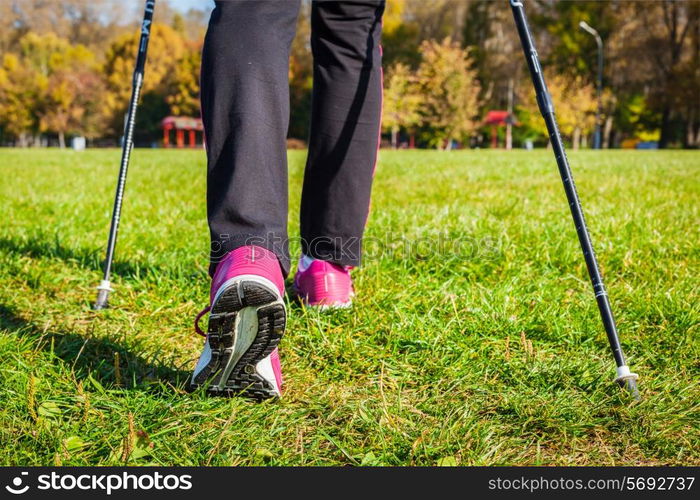 Nordic walking adventure and exercising concept - woman hiking, legs and nordic walking poles in summer nature