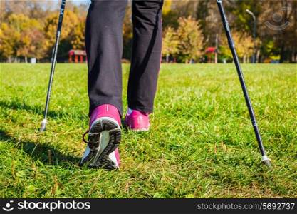 Nordic walking adventure and exercising concept - woman hiking, legs and nordic walking poles in summer nature