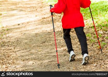 Nordic walking. Closeup of female legs hiking in the forest or park. Active and healthy lifestyle.