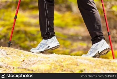Nordic walking. Closeup of female legs hiking in the forest or park. Active and healthy lifestyle.