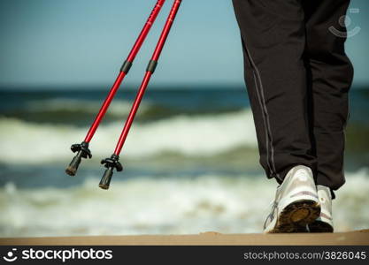 Nordic walking. Closeup of female legs hiking on the beach. Active and healthy lifestyle.