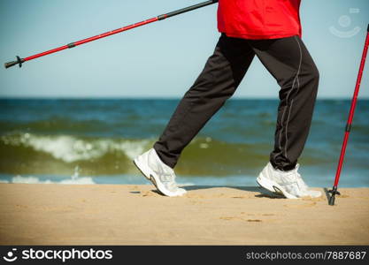 Nordic walking. Closeup of female legs hiking on the beach. Active and healthy lifestyle.