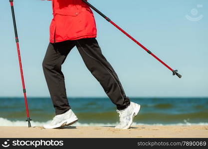 Nordic walking. Closeup of female legs hiking on the beach. Active and healthy lifestyle.