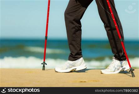 Nordic walking. Closeup of female legs hiking on the beach. Active and healthy lifestyle.