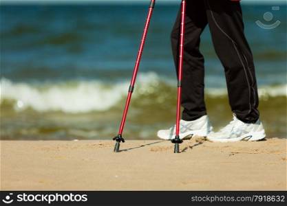 Nordic walking. Closeup of female legs hiking on the beach. Active and healthy lifestyle.