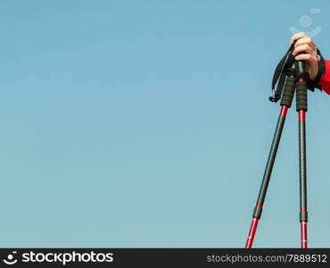 Nordic walking equipment. Closeup of red sticks on blue sky background with copy space. Active and healthy lifestyle.