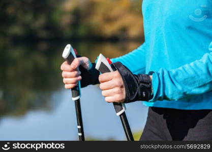 Nordic walking exercise adventure hiking concept - closeup of woman&rsquo;s hand holding nordic walking poles