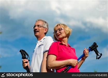 Nordic Walking - Happy mature or senior couple doing sports in summer outdoors