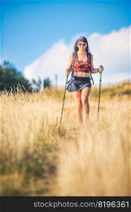 Nordic walking in the hills practiced by a beautiful young brunette woman alone