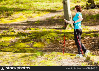 Nordic walking. Woman hiking in the forest or park. Active and healthy lifestyle.