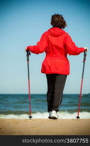 Nordic walking. Woman hiking on the beach. Active and healthy lifestyle.