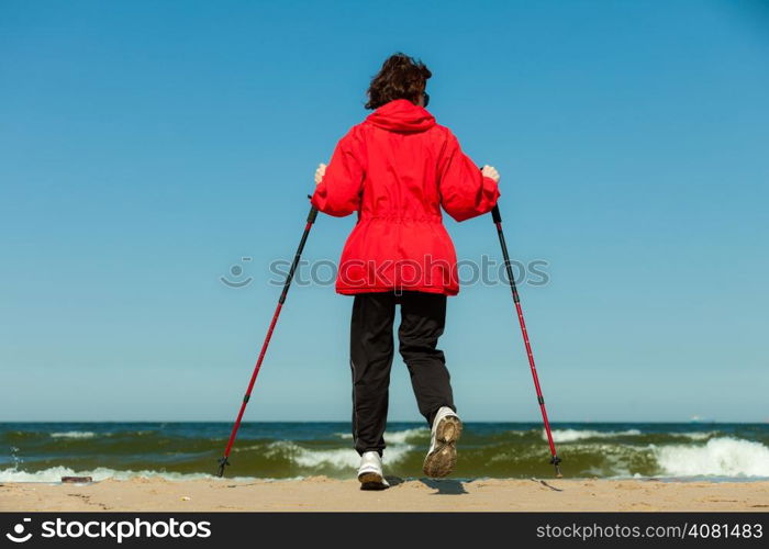 Nordic walking. Woman hiking on the beach. Active and healthy lifestyle.