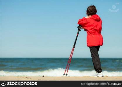 Nordic walking. Woman hiking on the beach. Active and healthy lifestyle.