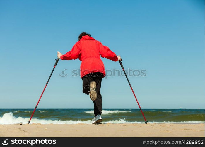 Nordic walking. Woman hiking on the beach. Active and healthy lifestyle.