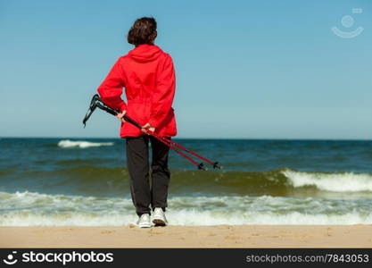 Nordic walking. Woman hiking on the beach. Active and healthy lifestyle.