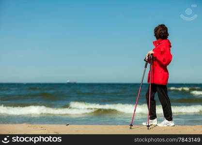 Nordic walking. Woman hiking on the beach. Active and healthy lifestyle.