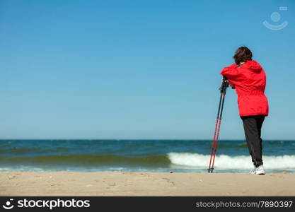 Nordic walking. Woman hiking on the beach. Active and healthy lifestyle.