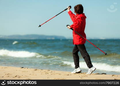 Nordic walking. Woman hiking on the beach. Active and healthy lifestyle.