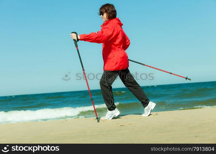 Nordic walking. Woman hiking on the beach. Active and healthy lifestyle.