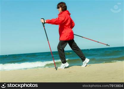 Nordic walking. Woman hiking on the beach. Active and healthy lifestyle.