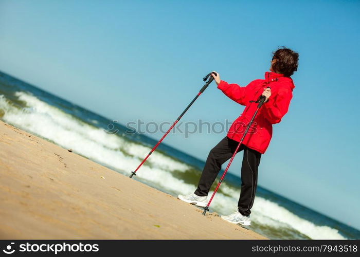 Nordic walking. Woman hiking on the beach. Active and healthy lifestyle.