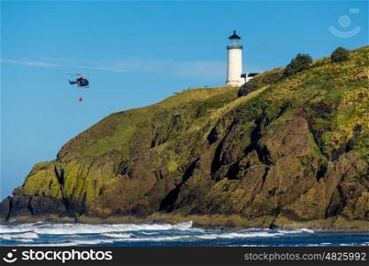North Head Lighthouse at Pacific coast, Cape Disappointment, built in 1898, WA, USA. Coast guard helicopter in the sky.