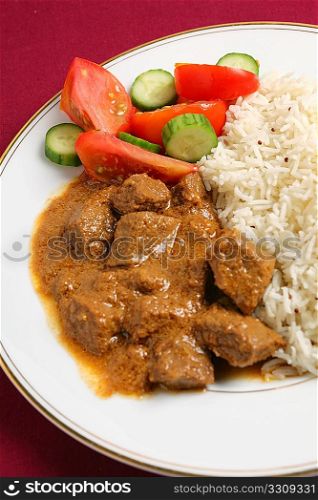 North Indian-style beef korma curry with basmati rice and a salad of tomato and cucumber