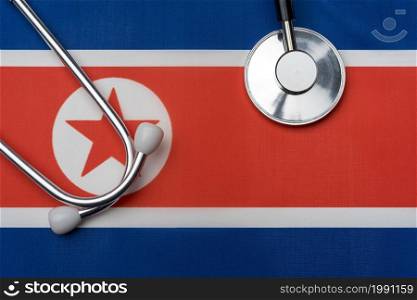 North Korean flag and stethoscope. The concept of medicine. Stethoscope on the flag in the background.. North Korean flag and stethoscope. The concept of medicine.