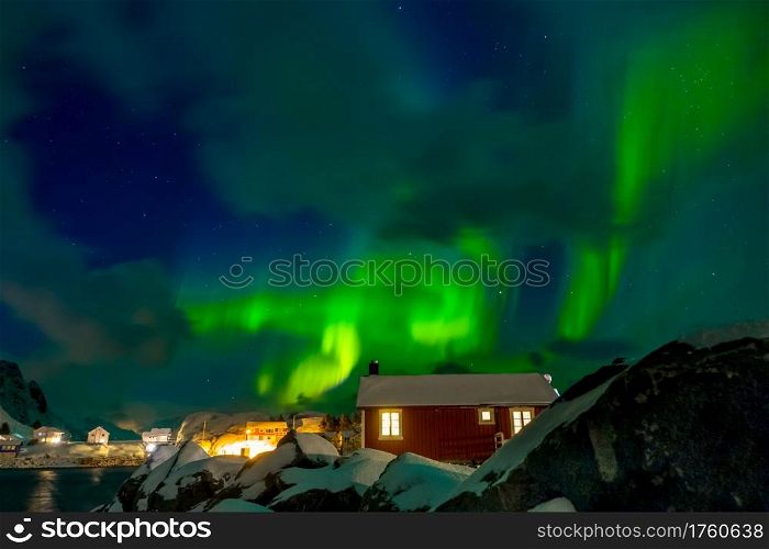 Norway. Lofoten. Hamnoya town. Winter night. Aurora Borealis above the roofs of houses. Northern Lights on the Norwegian Village