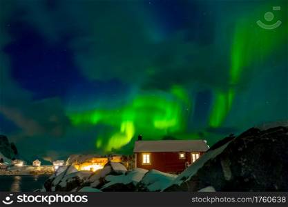 Norway. Lofoten. Hamnoya town. Winter night. Aurora Borealis above the roofs of houses. Northern Lights on the Norwegian Village