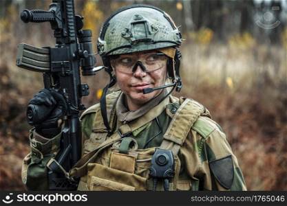 Norwegian Armed Forces Special Command FSK female soldier closeup portrait. Protective eye-wear and assault gun. Norwegian Armed Forces female soldier