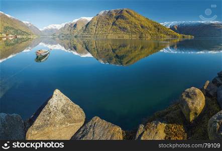 Norwegian autumn landscape a?? fjord with reflection of snow-capped mountains in clear water and fishing boat