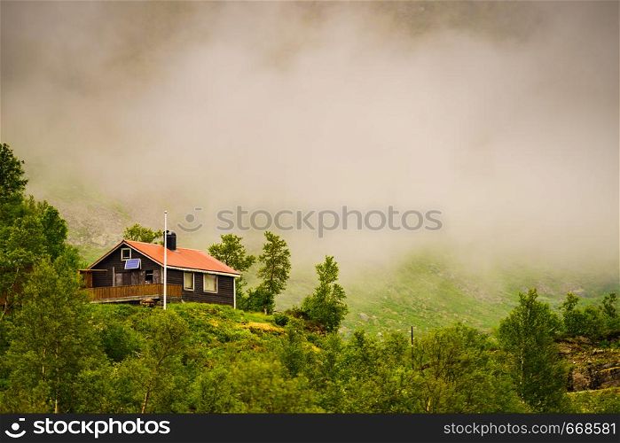 Norwegian country house cabin in mountains. Foggy misty landscape in Norway, Scandinavia. Norwegian country house in mountains.