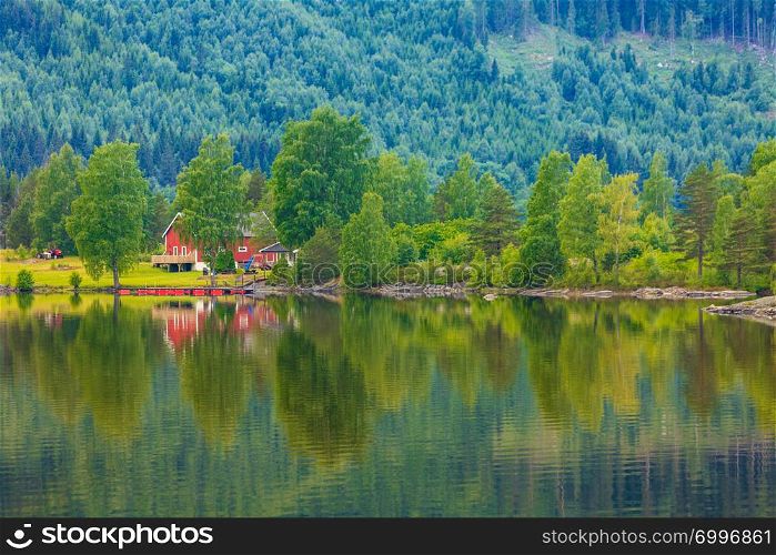 Norwegian country house in the mountains. Beautiful coastline fjords landscape in Norway, Scandinavia Europe. Norwegian country houses in mountains on lake shore