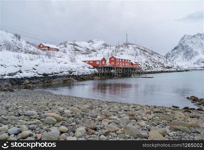 Norwegian fishing village in Reine City, Lofoten islands, Nordland, Norway, Europe. White snowy mountain hills, nature landscape background in winter season. Famous tourist attraction