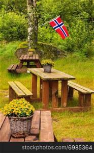 Norwegian flag and picnic site wooden table and benches outdoor in green forest park, Europe.. norwegian flag and green picnic site