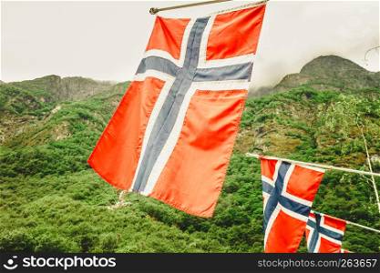 norwegian flag outdoor on green nature, mountains in the background. norwegian flag on green mountains background