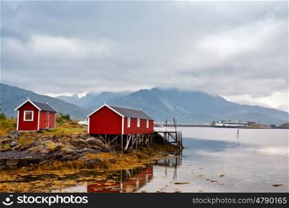 Norwegian hut rorbu on bay coast. Nordic cloudy summer day. Lofoten Norway islands.