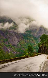 Norwegian landscape. Old road along fjord Eidfjorden in Norway Hordaland. Foggy rainy weather.. Old road along fjord Eidfjorden, Norway