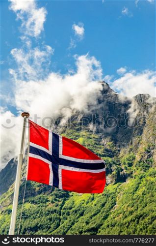 Norwegian national flag waving in the wind and mountain's peak in Neroy fjord, Aurlan, Sogn og Fjordane county, Norway