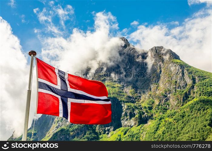 Norwegian national flag waving in the wind and mountain's peak in Neroy fjord, Aurlan, Sogn og Fjordane county, Norway