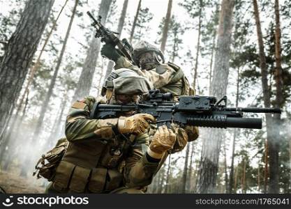 Norwegian Rapid reaction special forces FSK soldiers in field uniforms in action in the forest fog covering each other. Low angle view. norwegian soldiers in the forest