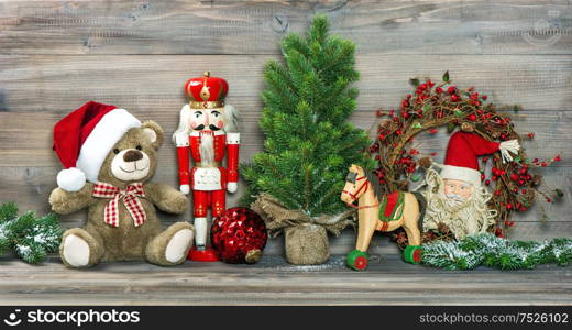 Nostalgic christmas decoration. Antique toys Teddy Bear in Santa Claus red hat and Nutcracker. No name mass production ware. Retro style toned picture