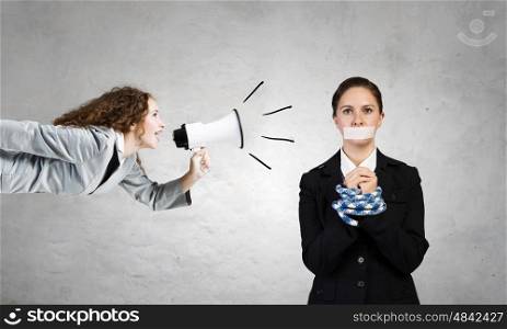 Not a word she dare to say. Young speechless businesswoman with tied hands and adhesive tape on mouth under aggressive pressure