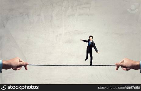 Not afraid to risk. Businessman walking on rope presenting risk and danger concept